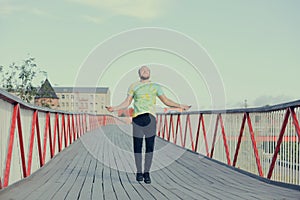 A young man in sportswear is jumping on jump ropes on bridge