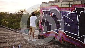 A young man with a spray can finishing draw a new graffiti on the wall. Video of the process of drawing a graffiti on a