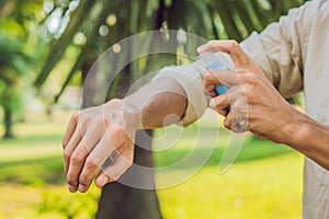 Young man spraying mosquito insect repellent in the forrest, insect protection