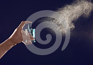 Young man spraying perfume on black background