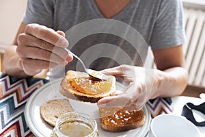 Young man spreading jam on a toast