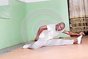 Young man spreading legs stretching in the gym.