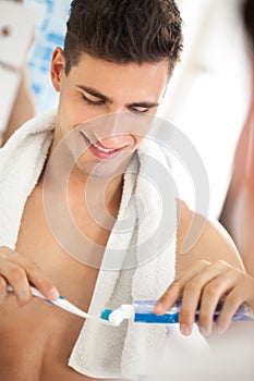 Young man squeezes toothpaste on the brush