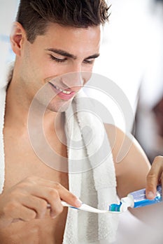 Young man squeezes toothpaste on the brush