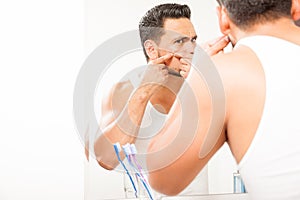 Young man squeezing a pimple
