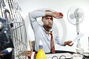 Young man ssuffering from the heat in the office