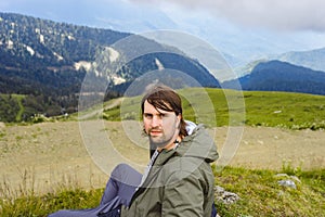 Young man stand in beautiful mountains on hiking trip. Active person resting outdoors in  nature. Backpacker camping outside