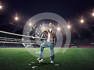 Young man standing on 3D football stadium and celebrate winning of many money. Sports betting success