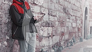 Young man standing against a wall background and using smartphone.