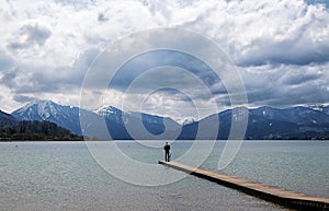 Young man standing alone on the jetty in the tegernsee lake and
