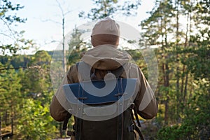 Young man standing alone outdoor with wild forest on background.