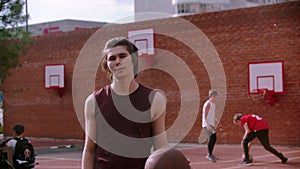 Young man standing on the basketball playground and hitting the ball