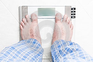 Young man standing on bathroom scale photo