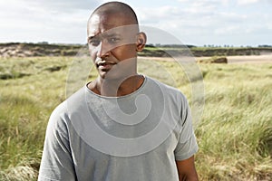 Young Man Standing On Beach Amongst Dunes