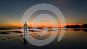 Young man standing on the beach at beautiful sunset