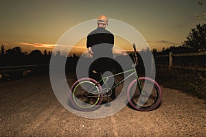 Young man standing bmx bike. BMX rider with and a sunset