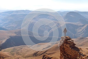 A young man is standing on a cliff. Looking at the Caucasian ridge. Mountain landscape. sunny day