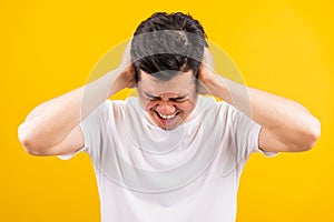 Young man standing he covering his ears with hands and shouting opened mouth shriek photo