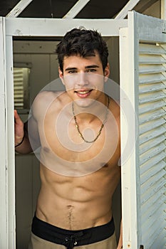 Young Man Standing in Doorway of Rustic Beach Hut