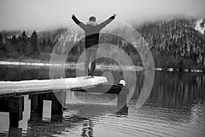 Young man standing at the end of wooden pier on a lake