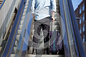 Young man standing on escalator with bag