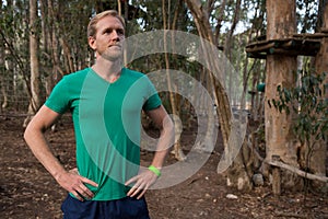 Young man standing in the forest while keeping his hands on waist