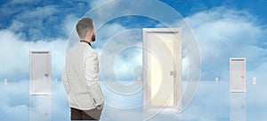 Young man standing in front of many doors against sky. Choice concept
