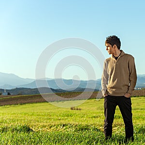 Young man standing in green field.