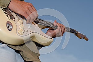 A young man standing guitarist happily under the blue sky in th