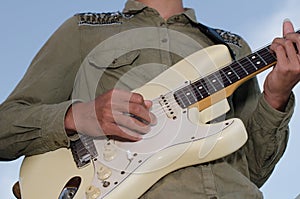 A young man standing guitarist happily under the blue sky in th