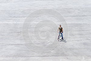 Young man standing with his bike on a square