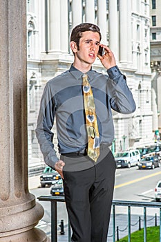 Young man standing inside office building in New York City, talking on cell phone