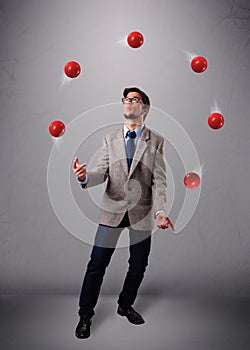 Young man standing and juggling with red balls