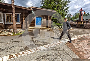 Young man standing on the line of the arctic circle in Rovaniemi