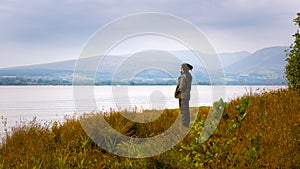 Young man standing by Loch Lomond, Scotland, UK