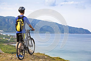 Young man standing on the mountain with bike