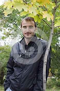 Young man standing near the autumn tree