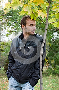 Young man standing near the autumn tree