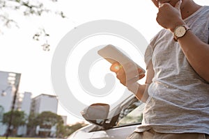 Young man is standing near the electric car and looks at the smart phone. The rental car is charging at the charging station for