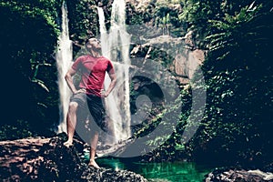 Young man standing near a waterfall in forest