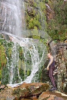 Young man standing next to waterfall