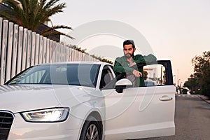 Young man standing by the open door of his car