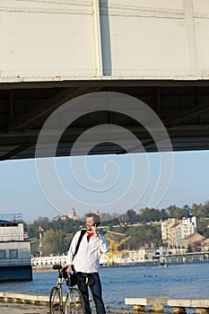 Young man standing outside with bicycle and mobile phone