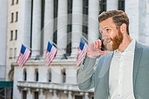 Young man standing outside office building in New York City, talking on cell phone