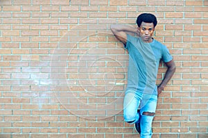 Young man standing posing brick wall outside cool attitude city lifestyle