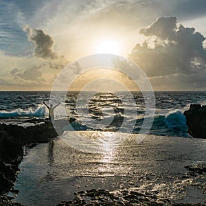 Young man standing with raised hands in front of raging sea