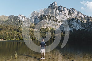 Young man standing on rock in Laudachsee with alps mountain. Summer Austria landscape
