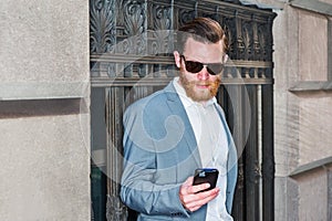 Young man standing on street in New York City, texting on cell phone