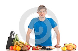 Young man standing at table with fruits. photo