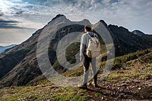 Young man standing on top of cliff mountains